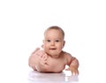 Happy curious infant child baby girl kid in diaper is lying on her tummy, stomach trying to reach, touch camera Royalty Free Stock Photo