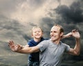 Happy laughing father with son with stormy sky background