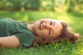 Happy laughing fun casual kid girl lying on the grass on nature summer background. Closeup Royalty Free Stock Photo