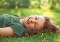 Happy laughing fun casual kid girl lying on the grass on nature summer background. Closeup positive Royalty Free Stock Photo