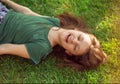 Happy laughing fun kid girl lying on the grass on nature summer background. Closeup positive outdoors bright sunny Royalty Free Stock Photo