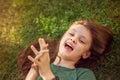 Happy laughing fun kid girl lying on the grass on nature summer background. Closeup positive outdoors bright sunny Royalty Free Stock Photo