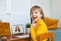 Happy laughing funny school student child girl with laptop at home. Online education and learning concept Royalty Free Stock Photo