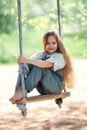 Happy laughing kid girl with long hair enjoying a swing ride on a sunny summer day Royalty Free Stock Photo