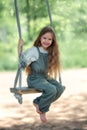 Happy laughing kid girl with long hair enjoying a swing ride on a sunny summer day Royalty Free Stock Photo