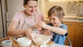 Happy laughing little boy mixing dough ingredients in big bowl. Children cooking with parents, little chef, family