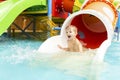 Little boy playing on water slide in outdoor pool on a hot summer day