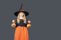 Happy laughing little girl in a carnival witch costume holding baskets for treats on a dark background Royalty Free Stock Photo