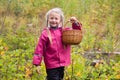 Happy laughing little girl is holding a wicker basket for picking wild berries Royalty Free Stock Photo