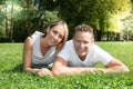 Happy laughing lovely young couple in love lying in green grass garden home outdoors summer day park Royalty Free Stock Photo