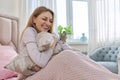 Happy laughing mature woman and green parrot at home in bed Royalty Free Stock Photo