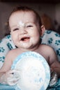 Happy messy baby boy sitting in highchair and playing with his dirty plate from yogurt Royalty Free Stock Photo