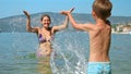 Happy laughing mother with son splashing sea water and having fun on beach. Family holiday, vacation and fun summertime Royalty Free Stock Photo