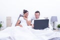 Happy laughing relaxed young couple using laptop in bed at home. Intermet and work at home concept Royalty Free Stock Photo