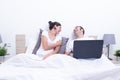 Happy laughing relaxed young couple using laptop in bed at home. Intermet and work at home concept Royalty Free Stock Photo