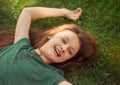 Happy laughing relaxing  kid girl lying on the grass on nature summer background. Closeup positive outdoors bright sunny Royalty Free Stock Photo