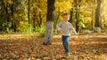 Happy laughing toddler boy running over fallen autumn leaves at park Royalty Free Stock Photo