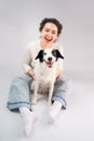 Happy laughing woman and her dog looking at camera sitting on grey floor. Royalty Free Stock Photo