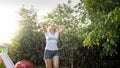 Happy laughing young woman dancing under rain at garden. Girl playing and having fun outdoors at summer Royalty Free Stock Photo