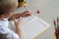 Happy left-handed boy writing in the paper book with his left hand, international left-hander day