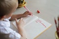 Happy left-handed boy writing in the paper book with his left hand, international left-hander day