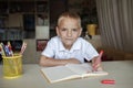 Happy left-handed boy writing in the paper book with his left hand, international left-hander day Royalty Free Stock Photo