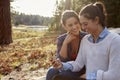 Happy lesbian couple using smartphone in the countryside