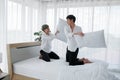 Happy LGBT Asian gay couple smiling playing pillow fight on bed at home. Young man smiling hitting boyfriend with pillows Royalty Free Stock Photo