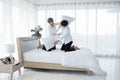 Happy LGBT Asian gay couple smiling playing pillow fight on bed at home. Young man smiling hitting his boyfriend with pillows Royalty Free Stock Photo