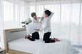 Happy LGBT Asian gay couple smiling playing pillow fight on bed at home. Young man smiling hitting his boyfriend with pillows Royalty Free Stock Photo