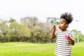 Happy little african american curly hair girl blowing soap bubbles playing alone in the park, Black hair style Royalty Free Stock Photo