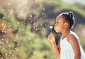 Happy little african american girl blowing dandelion flower outside. One cheerful black child having fun playing at the Royalty Free Stock Photo