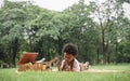 Happy little African boy lying down on mat and playing xylophone and wooden car toys at garden