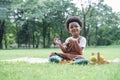 Happy little African kid boy holding a brush to paint in book while sitting on picnic mat in park Royalty Free Stock Photo