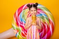 Happy little arab child girl in colorful striped dress drinking orange juice on yellow background Royalty Free Stock Photo