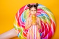 Happy little arab child girl in colorful striped dress drinking orange juice on yellow background Royalty Free Stock Photo
