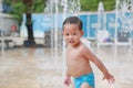 Happy little Asian baby boy having fun on water stream of a sprinkler. Kid playing in playground fountain in aqua park Royalty Free Stock Photo