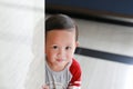 Happy little Asian baby boy hide behind a corner room. Small children playing peekaboo game indoor