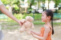 Happy little Asian child girl get a teddy bear doll from her mother in the park outdoor. Surprise gift from mom for daughter Royalty Free Stock Photo
