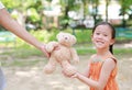 Happy little Asian child girl get a teddy bear doll from her mother in the park outdoor. Surprise gift from mom for daughter Royalty Free Stock Photo