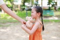 Happy little Asian child girl get a teddy bear doll from her mother in the park outdoor. Surprise gift from mom for daughter Royalty Free Stock Photo