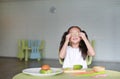 Happy little Asian child girl holding a piece of sliced cucumber on her eyes. Kid eating healthy food concept Royalty Free Stock Photo