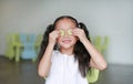 Happy little Asian child girl holding a piece of sliced cucumber on her eyes. Kid eating healthy food concept Royalty Free Stock Photo