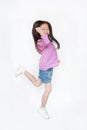 Happy little Asian child girl jumping in air on white background. Full length side view of smiling kid concept Royalty Free Stock Photo