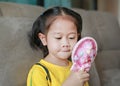 Happy little Asian child girl with make up and holding mirror