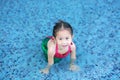 Happy little Asian child girl in a mermaid suit lying poolside with looking camera