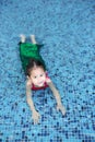 Happy little Asian child girl in a mermaid suit lying poolside with looking camera