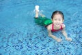 Happy little Asian child girl in a mermaid suit lying poolside with looking camera