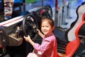 Happy little Asian child girl playing arcade video game. Racing car