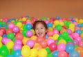 Happy little Asian child girl playing with colorful plastic balls playground